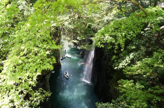 新緑の間から見下ろす高千穂峡の滝とボートが浮かぶ水面