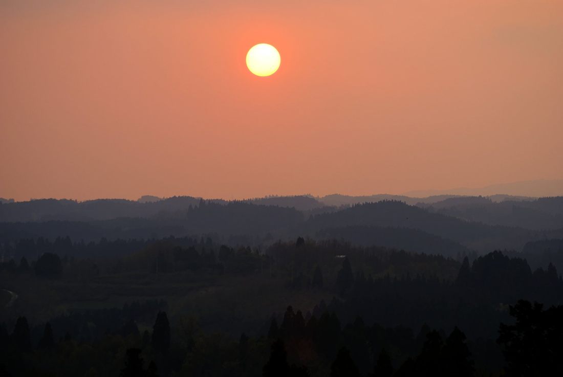 夕日に染まる山並みに沈む太陽